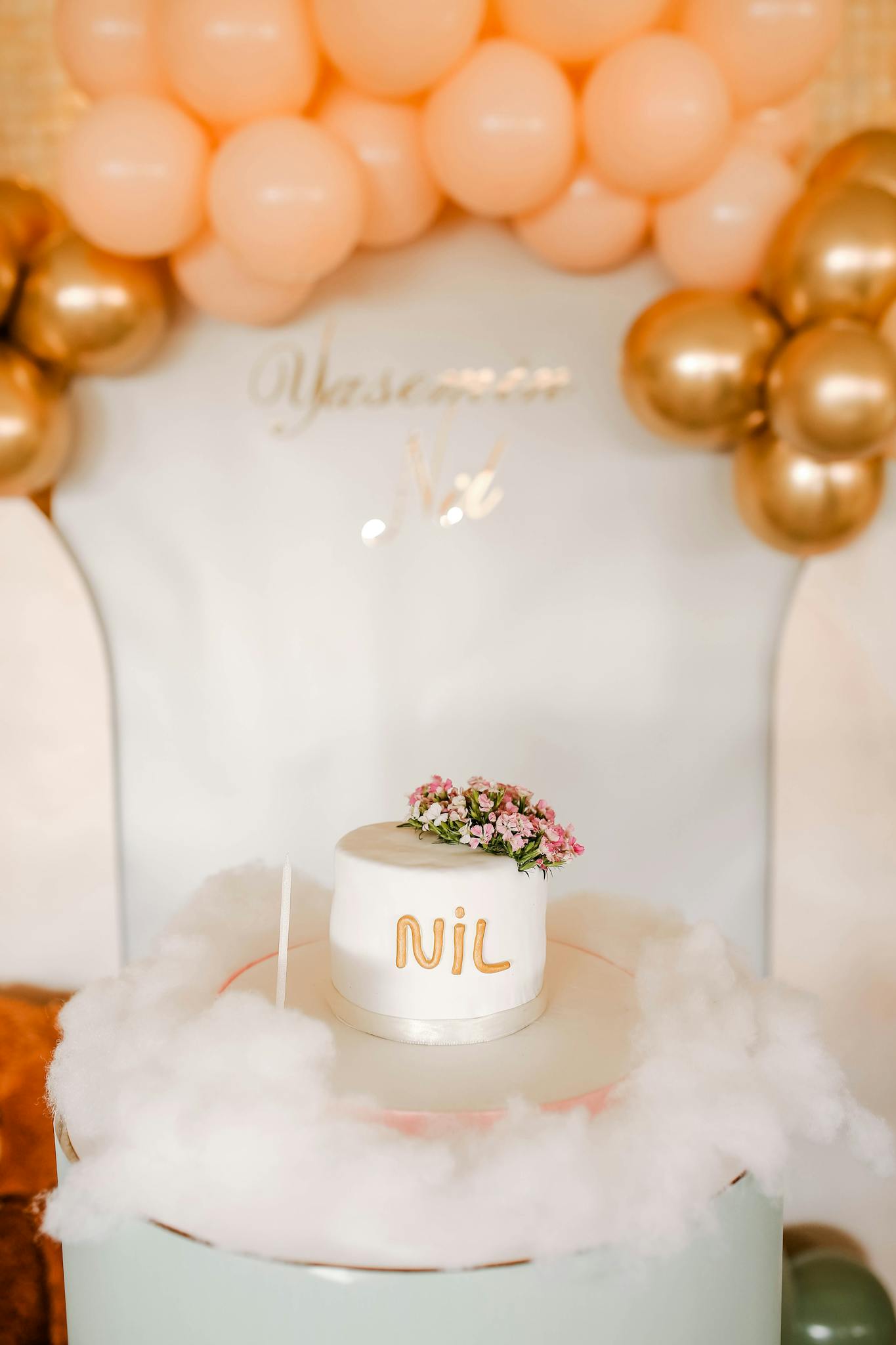 A beautiful celebration cake decorated with balloons and a floral accent, perfect for special occasions.