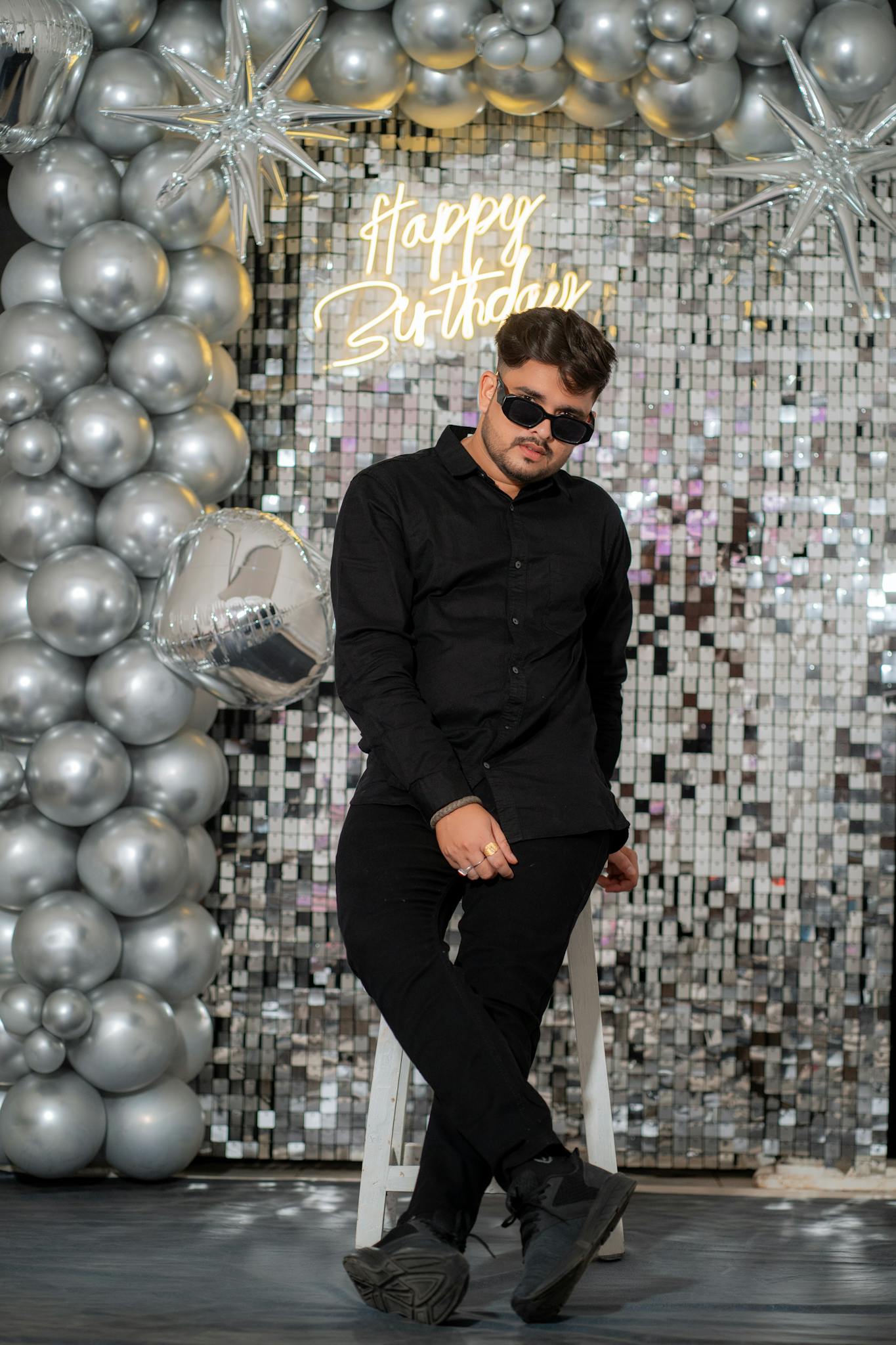 Stylish young man in sunglasses at a glamorous birthday party set in Anand, India with silver balloon decor.